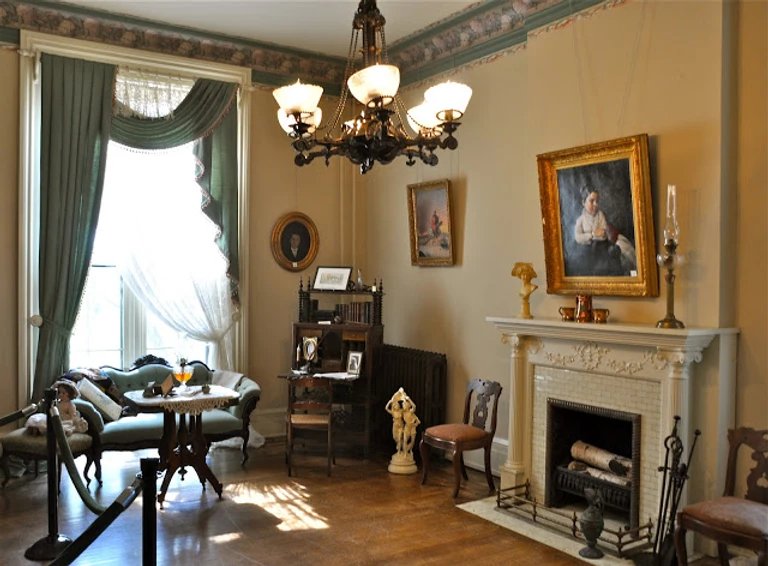 The parlor of the Long Home Museum with period furniture and a marble fireplace